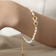 Bracelet fin en perles blanches naturelles avec motif infini en or serti de zircones scintillantes.