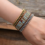 Bracelet multi-rangs ajustable en pierres bleues et marron avec perles dorées et argentées.