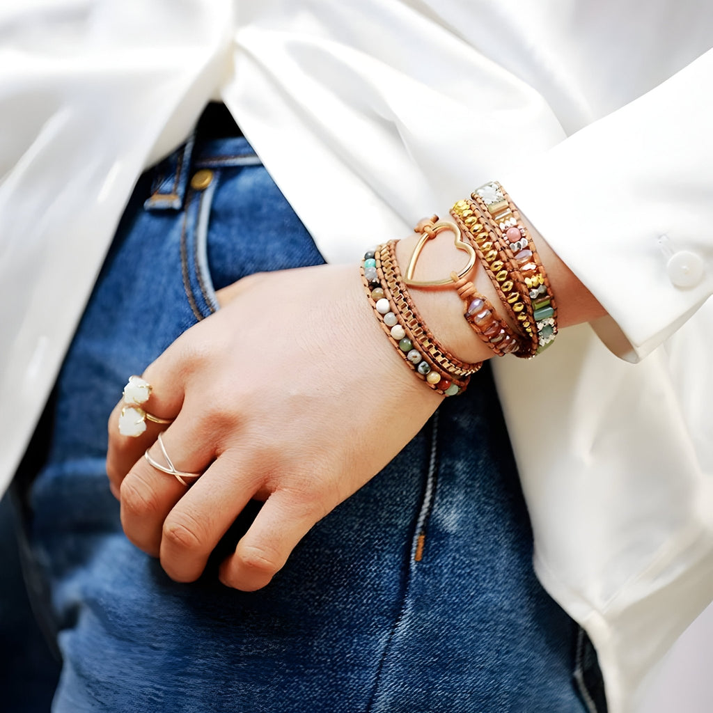 Bracelet femme multi-rangs en pierres naturelles colorées avec pendentif cœur doré, porté au poignet.
