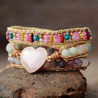 Bracelet multi-rangs en quartz rose, jaspe multicolore et cœur central en quartz rose sur fil beige.
