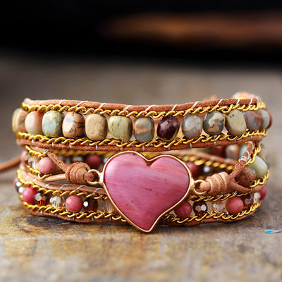 Bracelet multi-rangs en pierres naturelles multicolores avec cœur rose central en rhodonite et tressage en cuir beige.