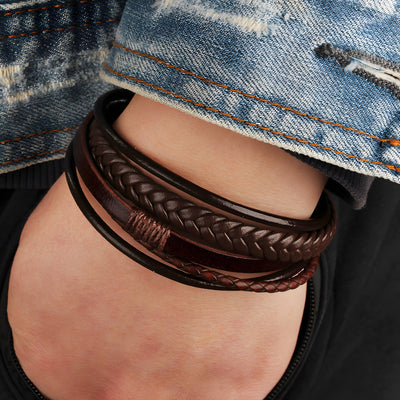 Bracelet multi-rangs marron en cuir tressé et lisse avec détails subtils porté au poignet.