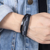 Bracelet multi-rangs gris et noir à motif damier avec fermoir métallique noir, porté au poignet.