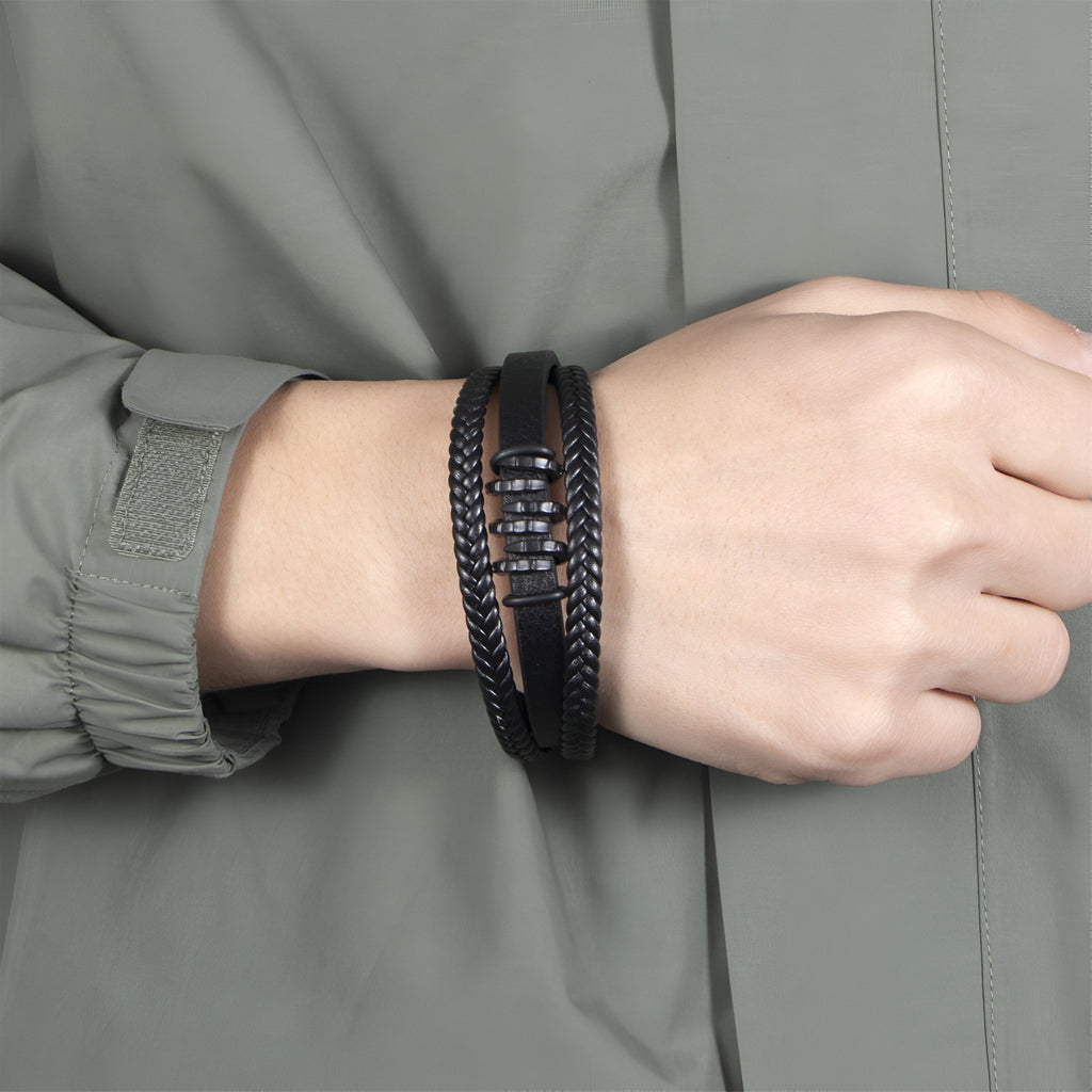 Bracelet multi-rangs noir en cuir avec motif ondulé et tresse, fermoir métallique noir.