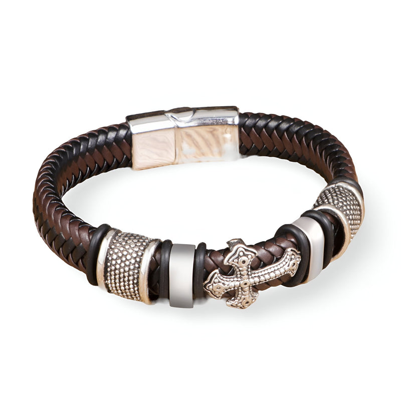 Bracelet marron en cuir tressé avec croix et détails métalliques argentés, fermoir magnétique.
