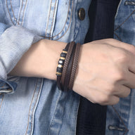 Bracelet multi-rangs marron en cuir tressé avec perles et détails en acier inoxydable doré.