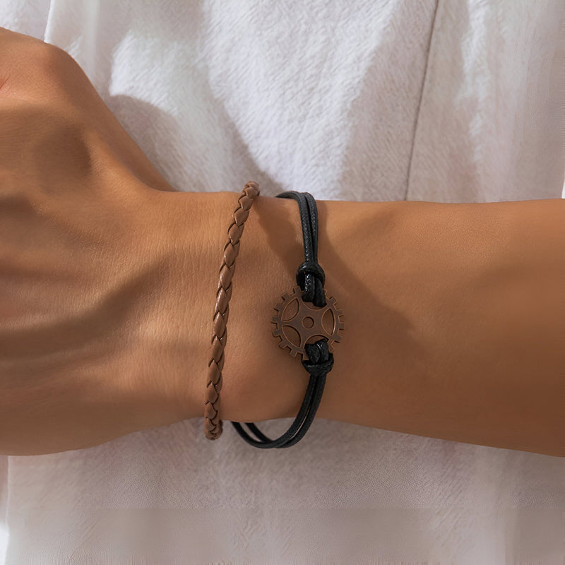 Bracelet multi-rangs homme en cuir marron tressé et noir avec pendentif gouvernail en métal vieilli.