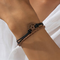 Bracelet multi-rangs marron avec gouvernail en métal noir et cordons tressés pour homme.