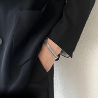 Bracelet double en titane argenté, maille fine et élégante, porté avec veste noire.