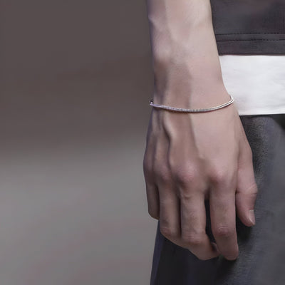 Bracelet fin en titane argenté en maille, porté au poignet masculin, style épuré.