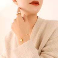 Bracelet en titane doré avec pendentif cœur discret porté au poignet féminin, style délicat et élégant.