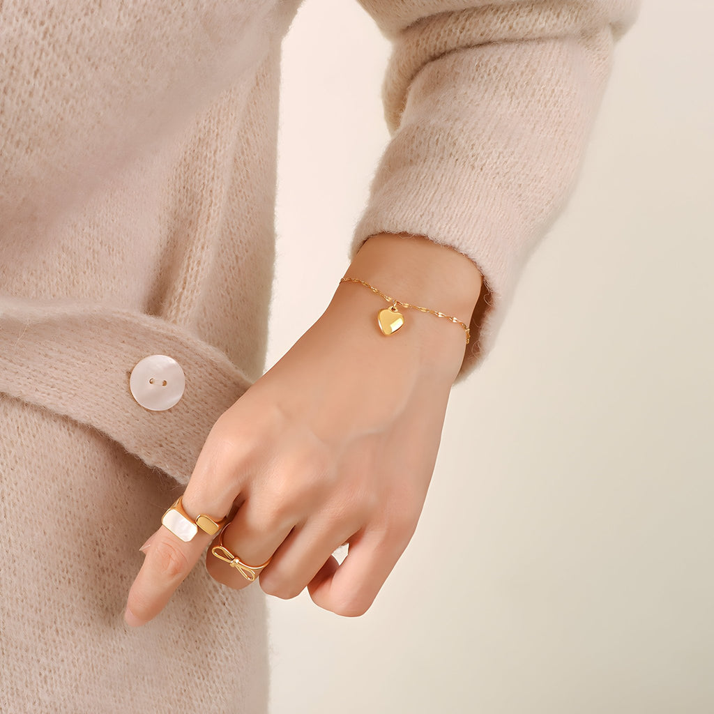 Bracelet en titane doré avec pendentif cœur discret, porté au poignet féminin.