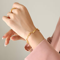 Bracelet en titane plaqué or 18 carats à maillons fluides et zircons scintillants porté au poignet féminin.