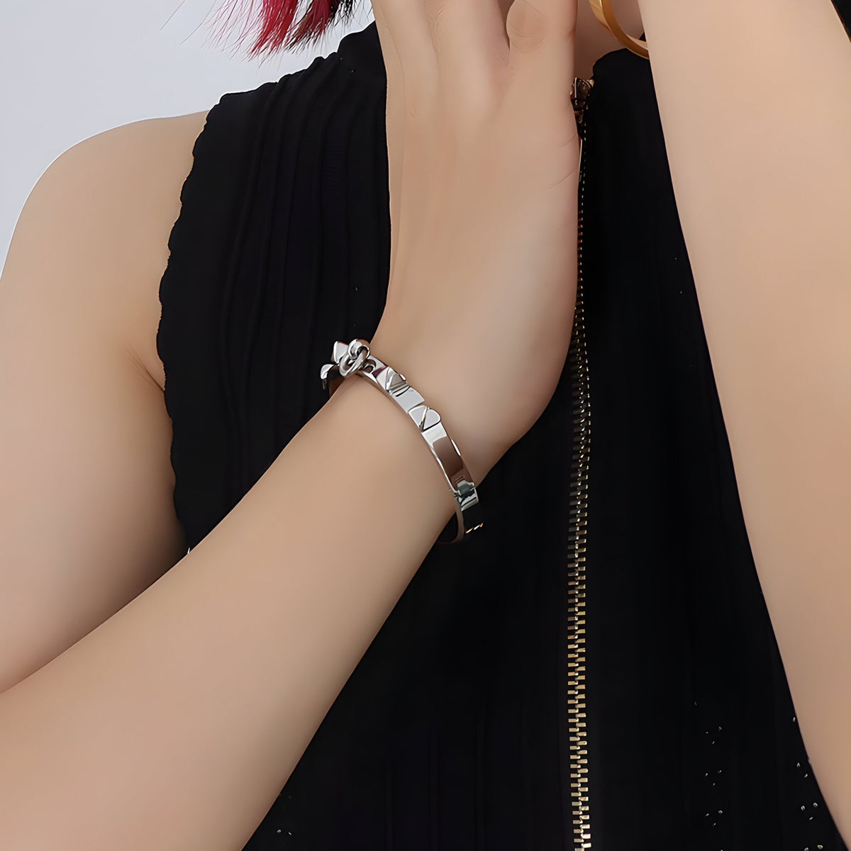 Bracelet fin en titane argenté avec piques carrées sur poignet féminin vêtu de noir.