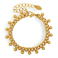 Bracelet en titane plaqué or 18 carats avec maillons larges et perles dorées pendantes.