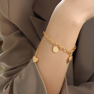 Bracelet chaîne en titane plaqué or 18 carats avec médaillons cœurs et cercle.