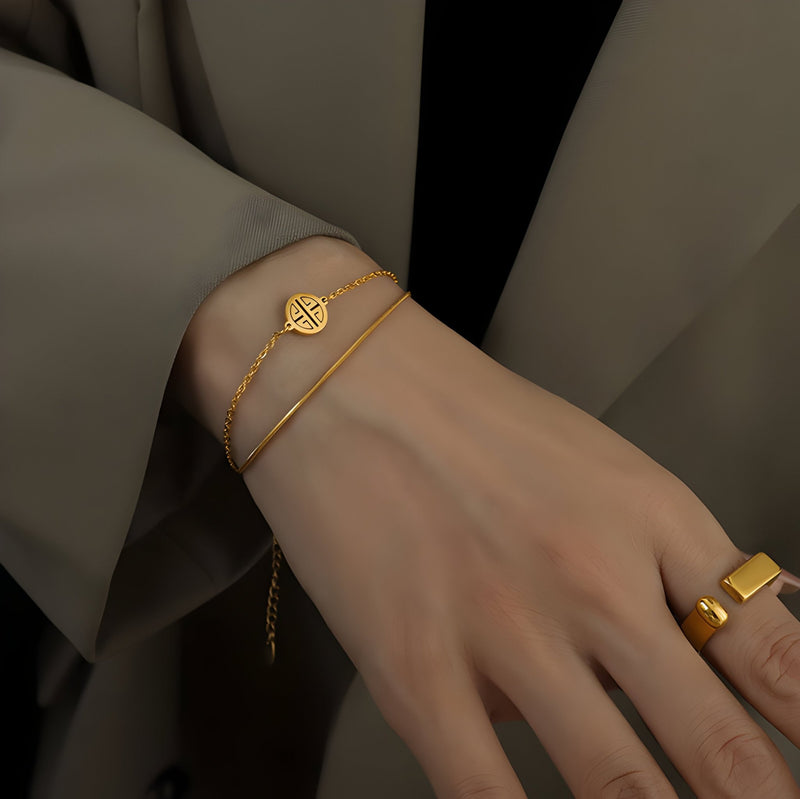 Bracelet en titane plaqué or 18 carats avec médaillon géométrique rond porté au poignet féminin.