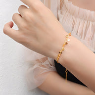 Bracelet fin en titane plaqué or 18 carats avec petits charmes ronds et délicats.