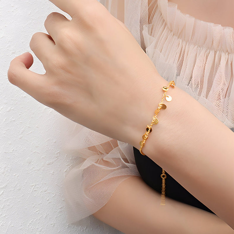 Bracelet fin en titane plaqué or 18 carats avec petits charmes ronds et délicats.