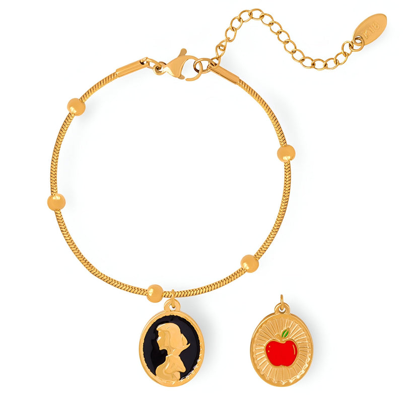 Bracelet doré fin avec pendentif silhouette blanche sur fond noir et pomme rouge en pendentif séparé.