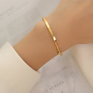 Bracelet fin en titane plaqué or 18 carats avec design distorsion original, porté au poignet.