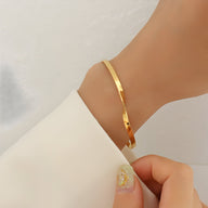 Bracelet fin en titane plaqué or 18 carats avec un design torsadé élégant porté au poignet.