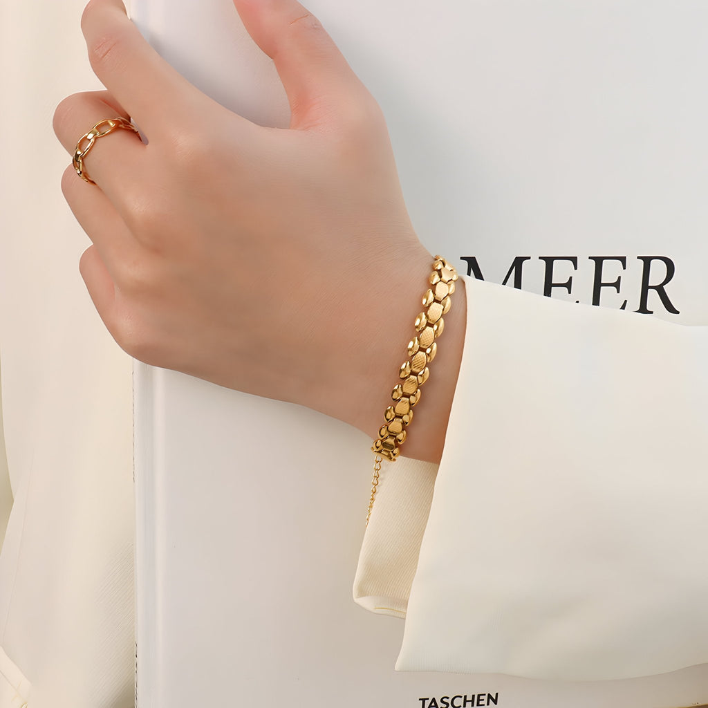 Bracelet en titane plaqué or 18 carats avec maille épaisse et finition brillante porté au poignet féminin.