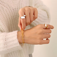 Bracelet en titane plaqué or 18 carats à maillons larges porté au poignet féminin avec pulls en maille crème.