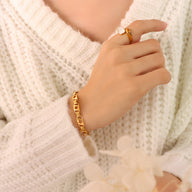 Bracelet fin en titane plaqué or 18 carats avec maillons rectangulaires sur poignet féminin.