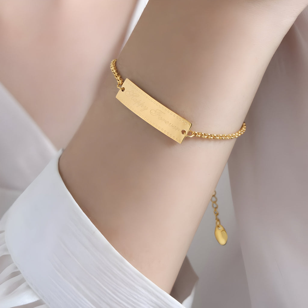 Bracelet chaîne fine en titane plaqué or 18 carats avec plaque rectangulaire lisse et fermoir ajustable.