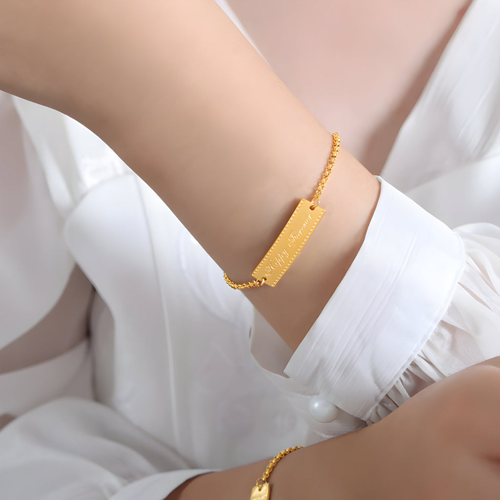 Bracelet en titane plaqué or 18 carats avec plaque gravée "Happy Forever" sur chaîne fine réglable.