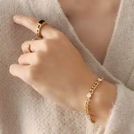 Bracelet en titane plaqué or 18 carats avec quatre zircons, chaîne maillons larges, porté au poignet féminin.