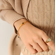 Bracelet jonc fin en titane plaqué or 18 carats avec étoile noire centrale, porté au poignet féminin.