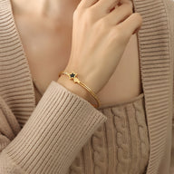 Bracelet jonc en titane plaqué or 18 carats avec étoile noire sur poignet féminin.