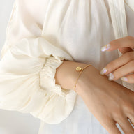 Bracelet fin en titane plaqué or 18 carats avec médaillon rond gravé, style délicat pour femme.