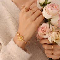 Bracelet rigide en titane plaqué or 18 carats avec médaillon floral élégant, modèle Léa, porté au poignet féminin.