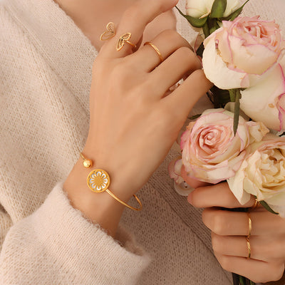 Bracelet rigide en titane plaqué or 18 carats avec médaillon floral élégant, modèle Léa, porté au poignet féminin.