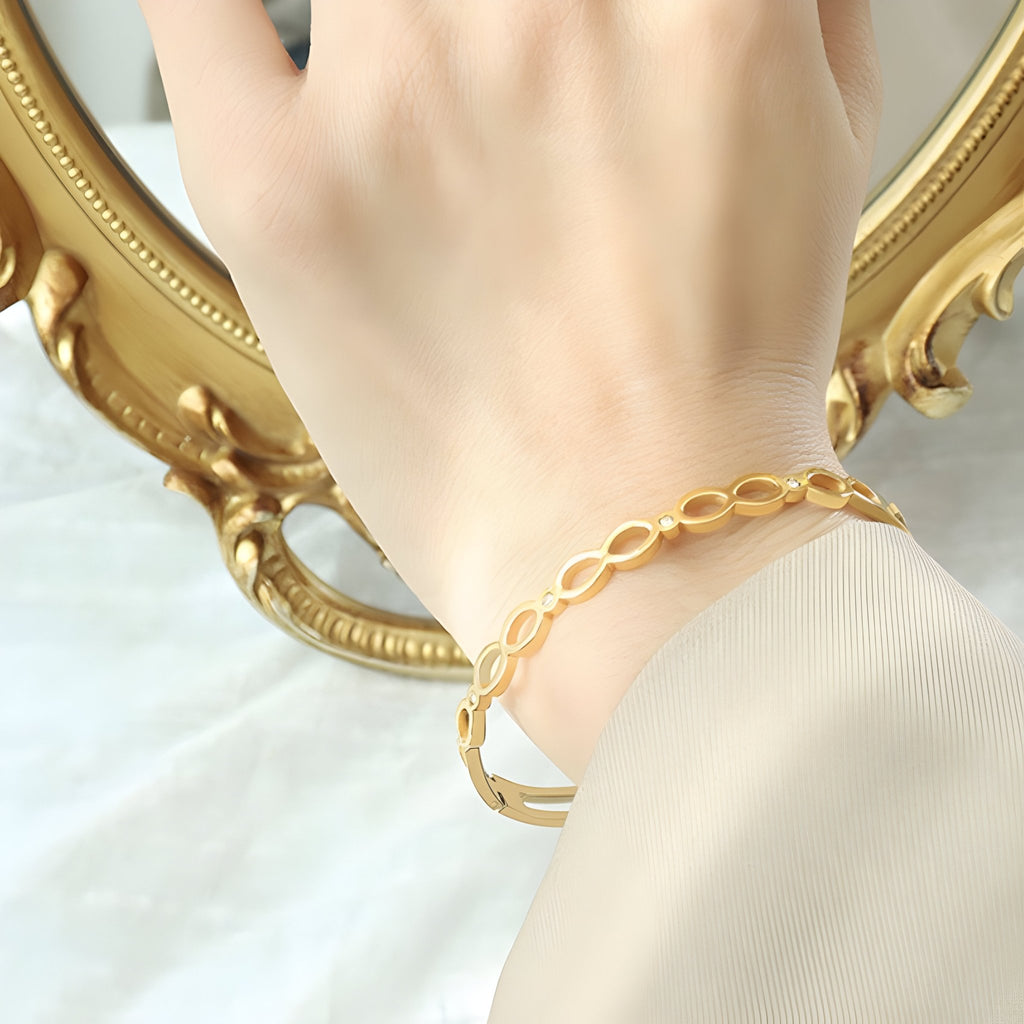 Bracelet en titane plaqué or 18 carats avec motif infini et pierres de zircon scintillantes.