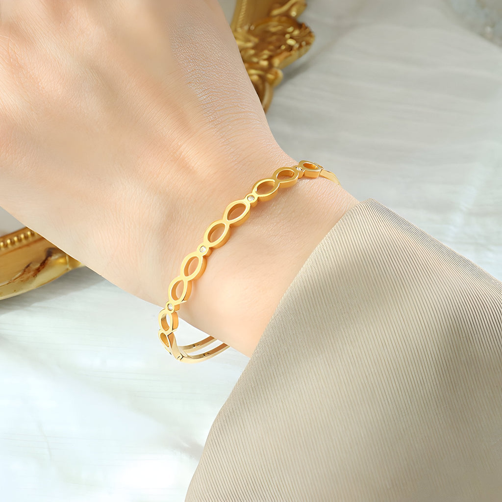 Bracelet en titane plaqué or 18 carats avec motifs infinis et détails en zircon sur poignet féminin.