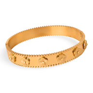 Bracelet jonc en titane plaqué or avec motifs fleurs en relief et bordure festonnée.