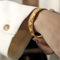 Bracelet jonc en titane plaqué or avec motifs de fleurs gravées, style délicat et élégant.