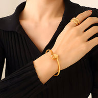 Bracelet rigide en titane plaqué or avec motif papillon orné de zircon sur poignet féminin.