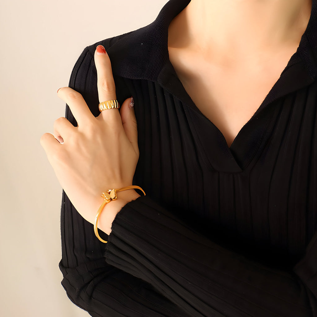 Bracelet en titane plaqué or fin avec zircon en forme de papillon porté au poignet, style élégant féminin.