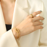 Bracelet en titane plaqué or à effet tressé avec anneau assorti porté sur poignet féminin.