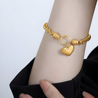 Bracelet en titane plaqué or avec maille torsadée et pendentif cœur brillant fermé par un anneau circulaire.