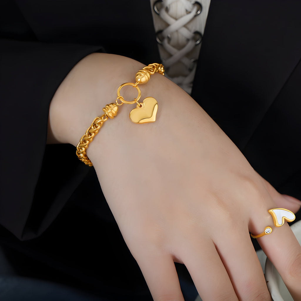 Bracelet en titane plaqué or à maille torsadée avec pendentif cœur brillant porté au poignet.