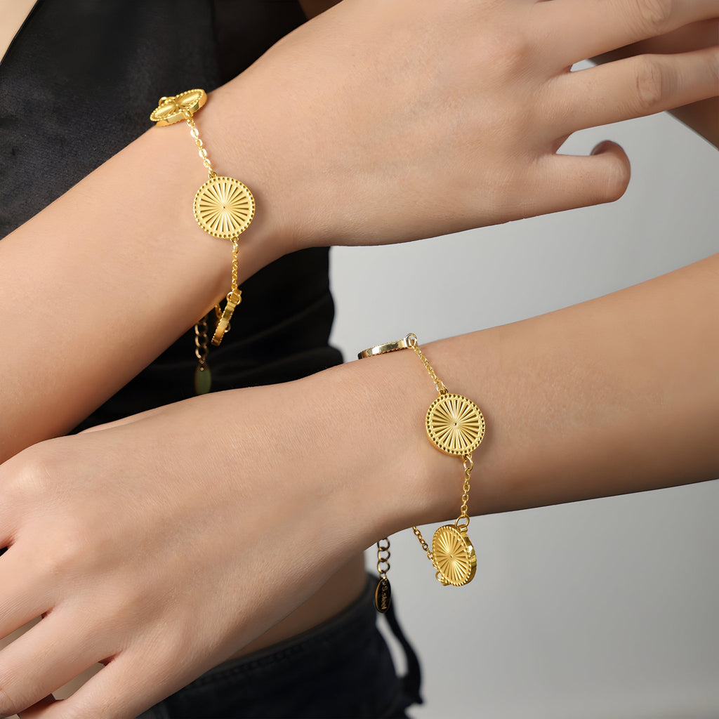 Bracelet en titane plaqué or avec médaillons rayonnants et chaîne fine élégante.