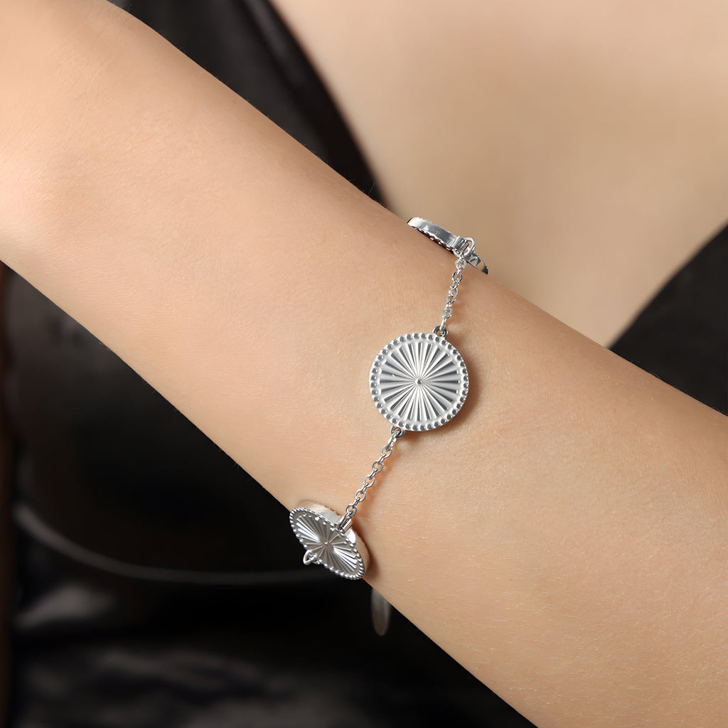 Bracelet en titane argenté avec médaillons rayonnants circulaires sur chaîne fine.