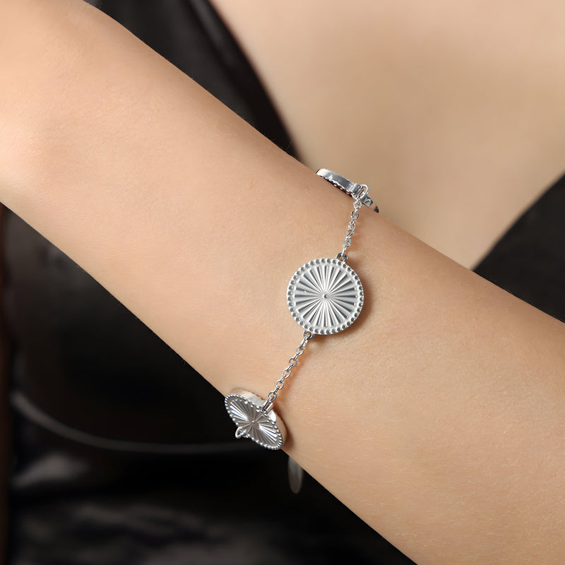 Bracelet en titane argenté avec médaillons rayonnants circulaires sur chaîne fine.