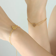 Bracelet en titane plaqué or avec motif cœur perlé délicat sur chaîne fine.